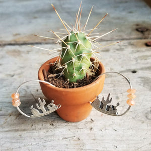 cactus hoop earrings with orange sunstone beads hanging from a tiny potted cactus