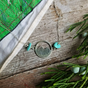 silver mountain necklace with turquoise beads with a juniper sprig and the edge of a map