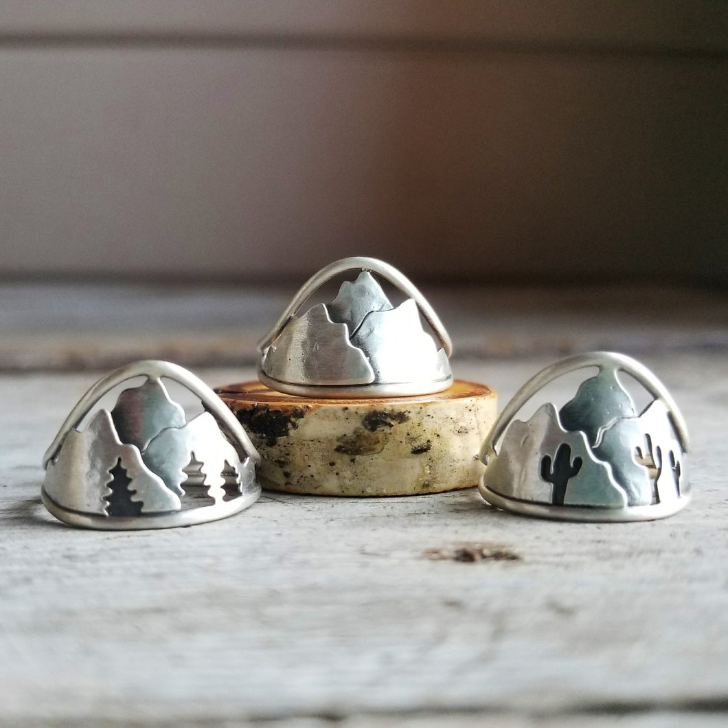 three silver mountain rings with pine trees and cactus silhouettes